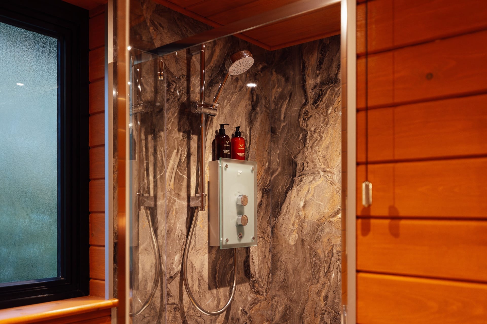 Walk-in electric shower with marble panelling and Odyssey toiletries